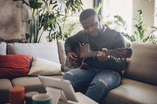istock Joyful Man Playing Guitar at Home 1939904707