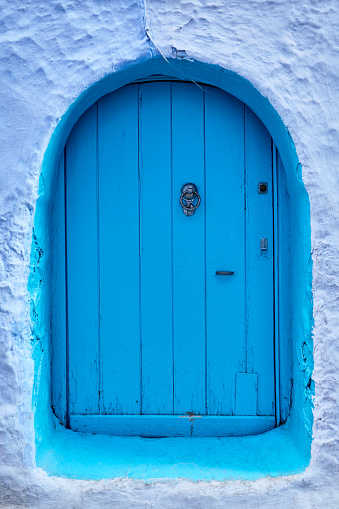 Door and windows painted in blue . White villa entrance . Rustic house with windows and door at white wall
