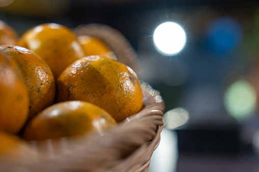 Orange fruits in a wooden basket to make orange juice in a restaurant at night.