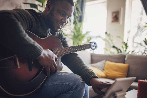 istock Joyful Man Playing Guitar at Home 1939906280