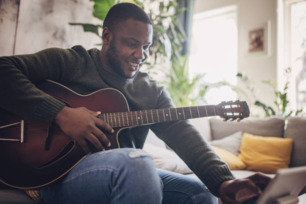 istock Joyful Man Playing Guitar at Home 1939906856