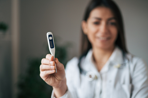Female doctor holding digital thermometer