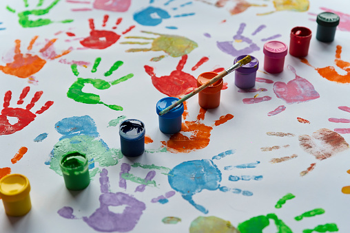 Multi coloured palm of hand of child on a white paper. Painting activity, creativity and fun for children. Handprint backgrounds.