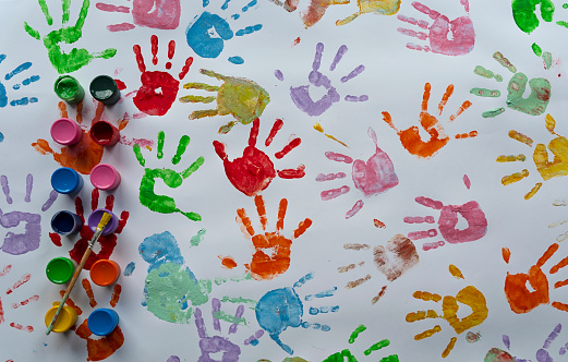 Multi coloured palm of hand of child on a white paper. Painting activity, creativity and fun for children. Handprint backgrounds.