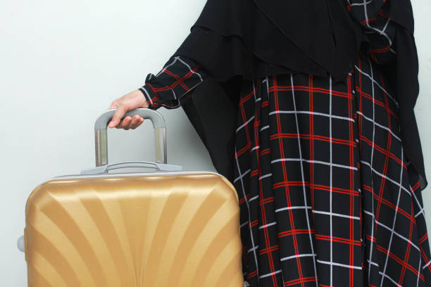 istock Muslim woman's hand holding a gold suitcase. 1939914485