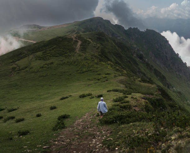 istock A lone hiker traverses a rugged mountain path as a dramatic overcast sky looms above, highlighting the quiet solitude of nature at dusk. 1939926926