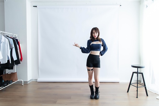 Asian woman in a blue crop top and black shorts posing in front of a white background