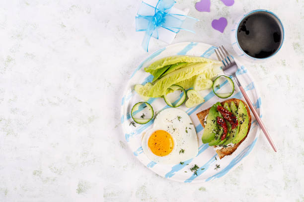 istock Romantic breakfast for Valentine's Day. Fried egg and toast with avocado and cream cheese. Top view 1939939678