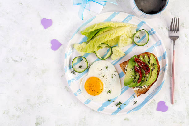 istock Romantic breakfast for Valentine's Day. Fried egg and toast with avocado and cream cheese. Top view 1939939680