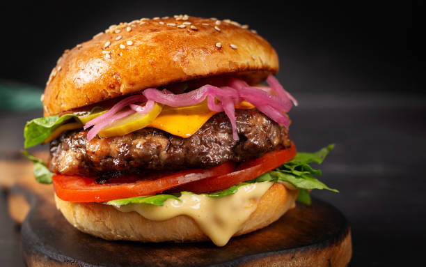 Beef hamburger. Sandwich with beef burger, tomatoes, cheese, pickled cucumber and lettuce. Cheeseburger.