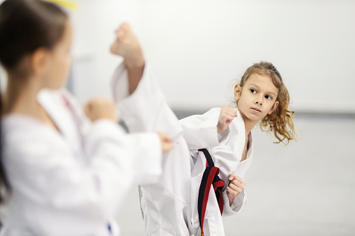 A taekwondo kid is practicing combat in martial art school.