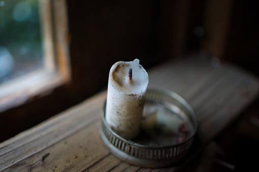 Extinguished candle placed by the window of an old house