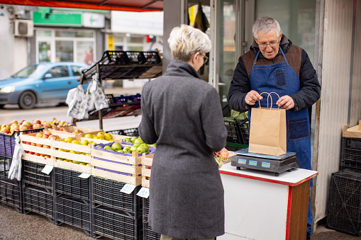 A mature Caucasian woman buying fruits and vegetables from a local farmer's market