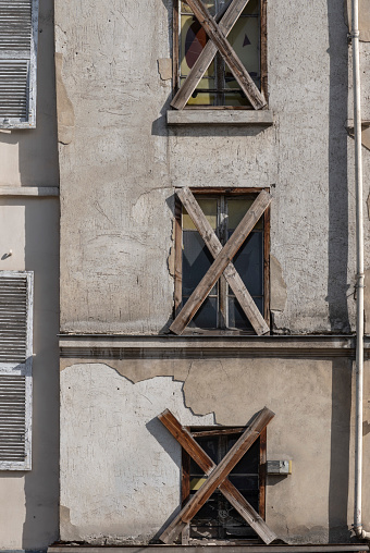 Paris, France - 09 23 2023: View of an old building facade with the windows blocked with wooden boards