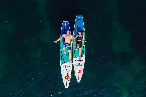 July 24, 2022. Antalya, Turkey. Couple relaxing on stand up paddle board at sea. People on Red paddle sup board in Mediterranean sea. Aerial view