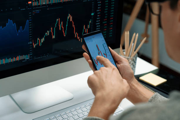 istock Investors pointing on screen with smartphone with laptop in stock. Pecuniary. 1939989029