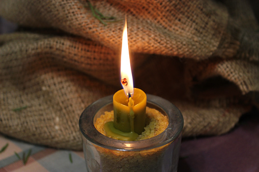 Traditional Candle Injected In Wheat Corns Inside Glass Burning In Front Of Spruce In Craft Folded Fabric