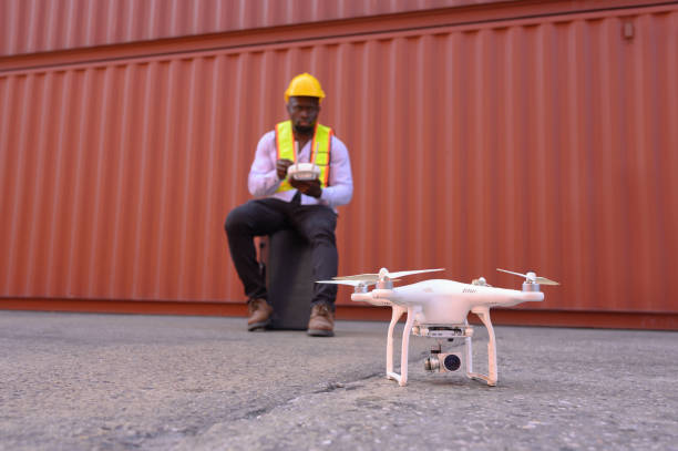 istock An engineer or worker uses a remote control to control a drone at a container port to inspect containers. Foreman uses a remote-controlled drone with camera flying on a container ship at a shipping po 1940016123