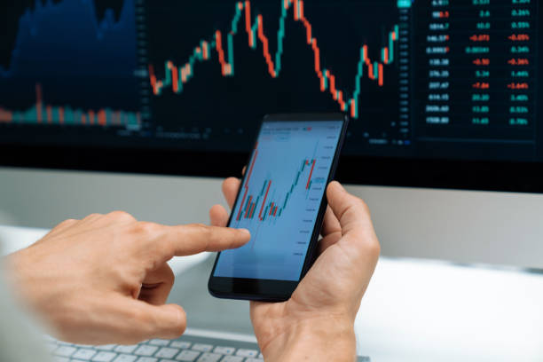 istock Investors pointing on screen with smartphone with laptop in stock. Pecuniary. 1940042393