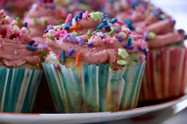 istock Strawberry Frosted Cupcakes with Rainbow Sprinkles, One in Foreground Focus with Blue Wrapper 1940049214