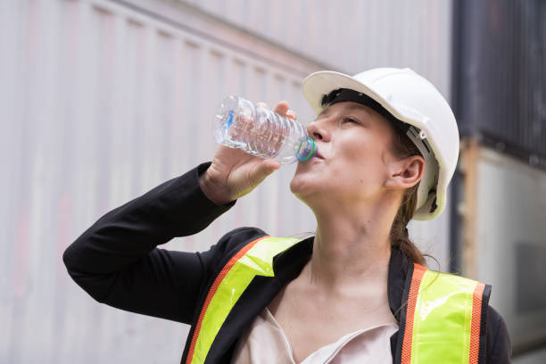 istock Female container worker drinking water in break time at commercial dock site 1940050284