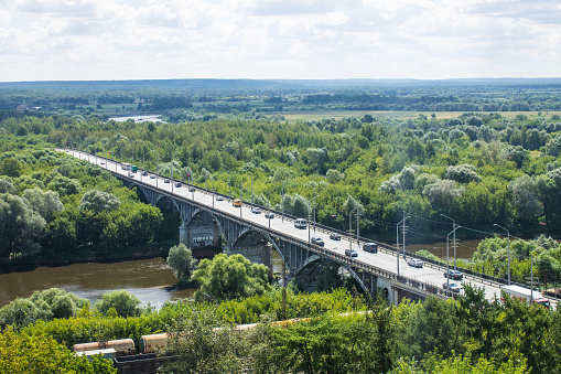 Top view panorama - a road bridge over the Klyazma river among the lush foliage of green trees on a sunny summer day and a beautiful horizon in Vladimir Russia