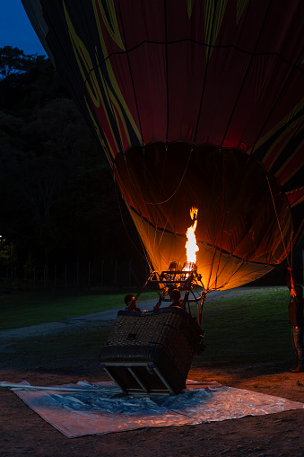 Hot air balloon is inflated in the early morning hours by a Latino man with an average age of 50 years who is the pilot in charge of providing this experience to tourists.