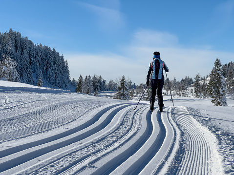 beautiful active senior woman cross-country skiing in fresh fallen powder snow in the in the Tannheim Valley, Tyrol, Austria