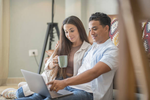 istock Young couple moving to a new home relaxing sitting on the sofa using computer laptop, smiling happy for moving to new apartment 1940074623