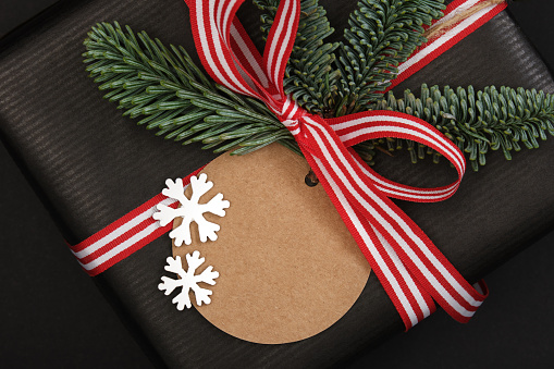 Gift box with fir tree sprig and label on dark background. Space for your text