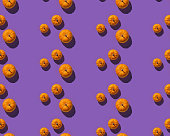 Pattern with orange pumpkins on purple background