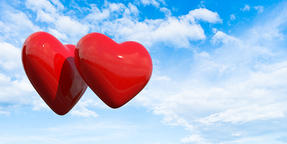 Two red hearts in a bright and slightly cloudy sky. In the concept of the passion of love and the first excitement. Large copy space on the sky. Easily changeable background and cuttable objects thanks to clipping path feature.