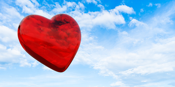 Reflective red heart in a bright and slightly cloudy sky. In the concept of the passion of love and the first excitement. Large copy space on the sky. Easily changeable background and cuttable objects thanks to clipping path feature.