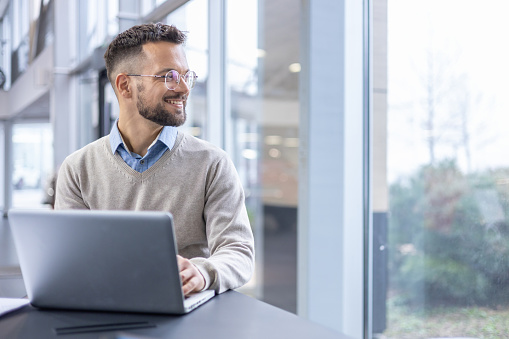 A man sitting in front of a laptop computer, working in an office.