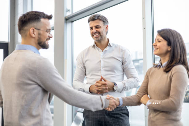istock Business Professionals Shaking Hands in Front of Office Window 1940103909