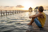 Man on pier above lake at sunrise contemplating nature
