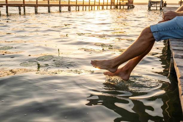 30's man on a pier above the beautiful lake of Bacalar, MexicoFeet dangling from the wooden path.