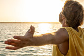 Man standing arms outstretched on a pier at sunrise