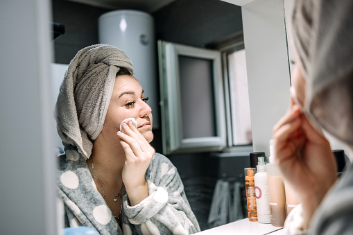 Woman applying face cream before putting make-up.