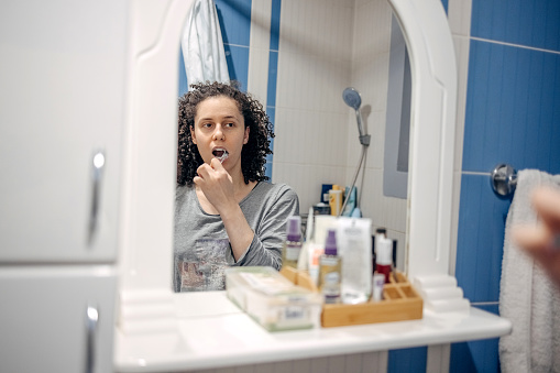 Woman brushing teeth as part of morning routine.