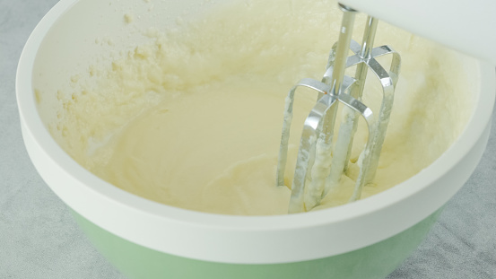 Cream cheese whipped cream recipe. Mixing cream cheese, sugar powder, and whipping cream together in a bowl. Close-up preparation process