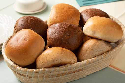 Basket with a variation of fresh baked white and brown buns of bread close up on the table