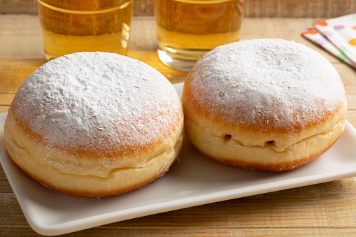 Dish with two fresh baked Berliner donuts covered with white sugar close up