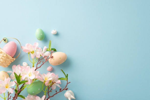 istock Springtime joy captured: top view miniature basket, vibrant eggs, a sweet bunny, apple blossoms on a pastel blue background. Customizable space for your message 1940150632