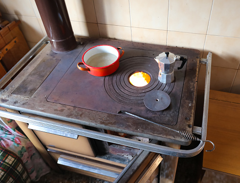 wood stove in the  kitchen of a house in the mountains and the fire lit while heating a pot and the moka to make coffee