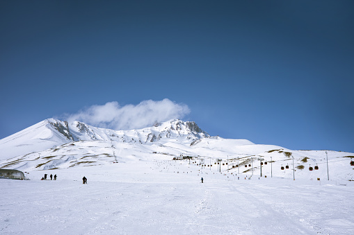 Snow-covered mountain with ski slope and lifts in a European ski resort against a blue cloudy sky. Nature, beautiful views.  Vacation. Travel content