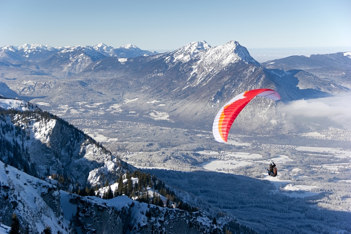 Hochalm, Austria- 13 January 2024: A paraglider flying over a winter landscape in Salzburg, Austria. He started from the mountain station Untersberg, Salzburg.