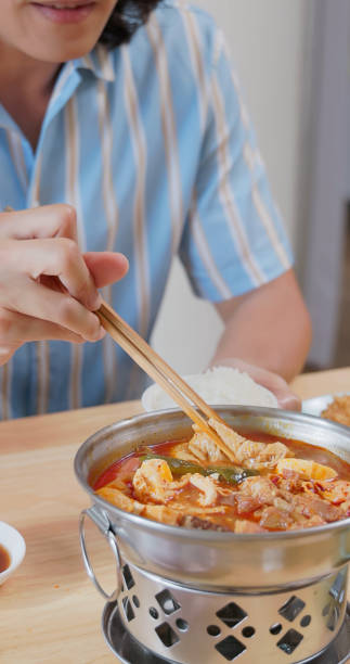 Korean food (Kimchi Jjigae), Kimchi soup with tofu, pork, scallion and chili in Korean stone bowl on black background
