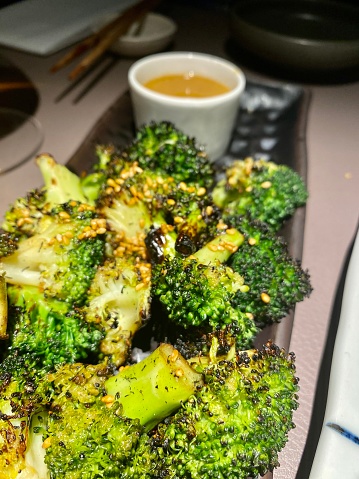 The grilled broccoli at Sticks'n'Sushi in Kingston upon Thames, Surrey, London, England, UK, is a delectable dish served with a flavorful white miso sauce. The dish showcases the vibrant colors and textures of the broccoli, and the miso sauce adds a rich and savory component to elevate the overall taste. This close-up shot captures the enticing details of the food, highlighting the care and presentation that goes into the culinary experience at Sticks'n'Sushi.