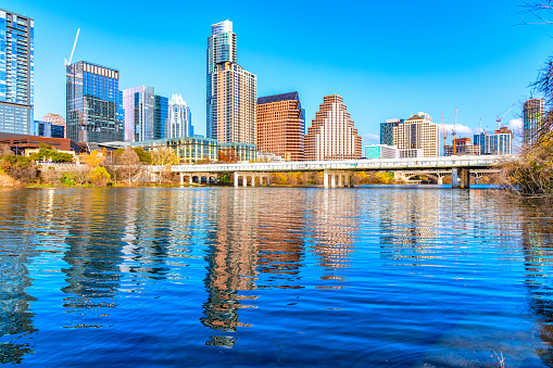 The skyline of downtown Austin, Texas on a clear afternoon with the reflection of the buildings in the Colorado River.